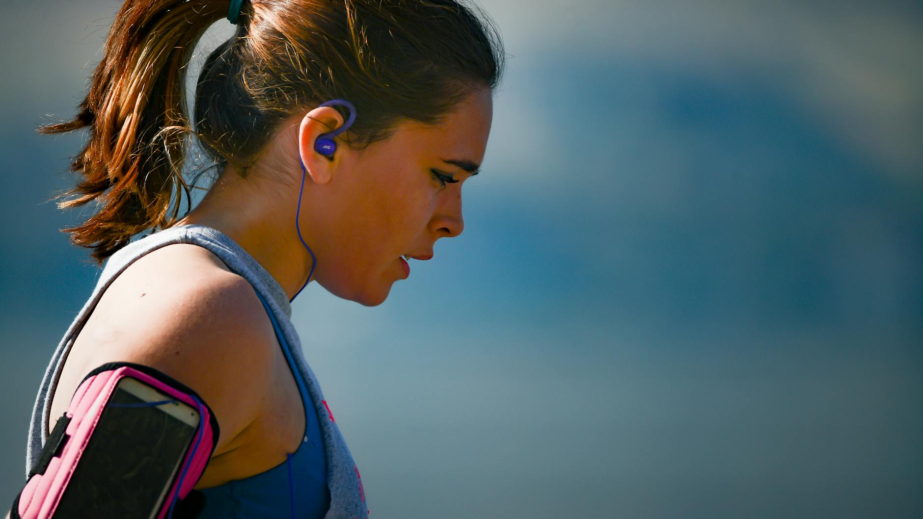 woman wearing smartphone armband and blue earphones